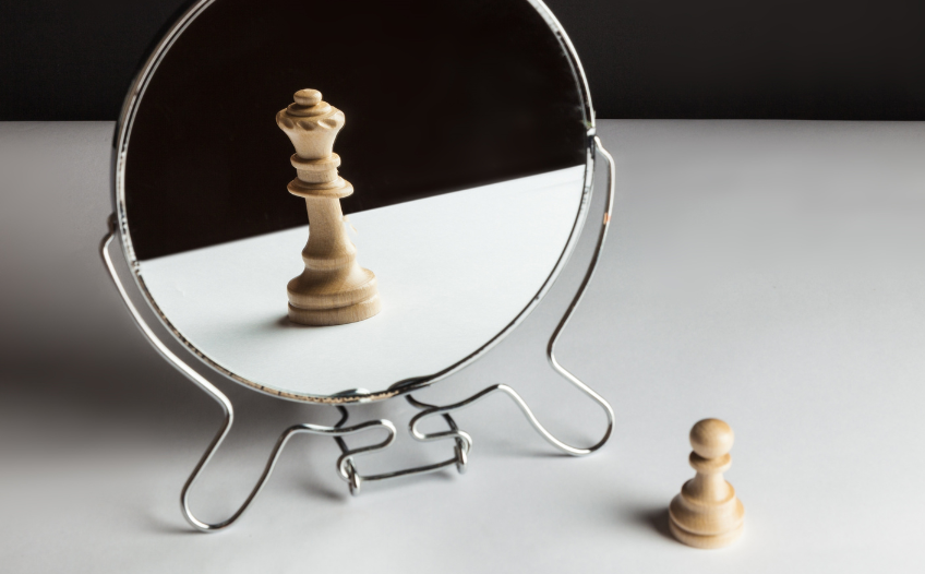 Chess pawn piece seeing a queen piece in the mirror